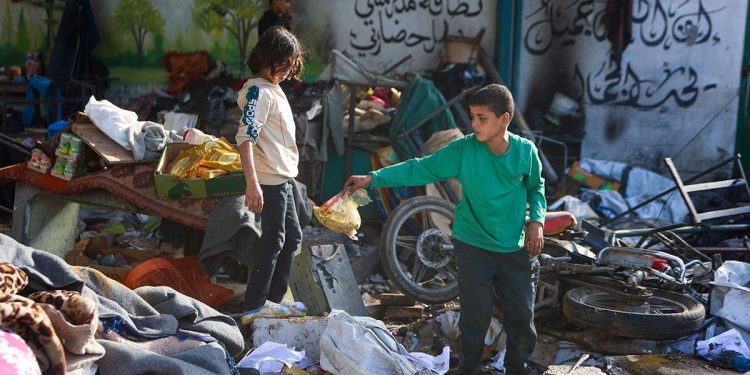 Niños buscan sus cosas entre los escombros de escuela bombardeada en Gaza