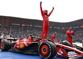 Piloto de Ferrari celebra de pie sobre su monoplaza tras ganar el Gran Premio de la Ciudad de México ante miles de aficionados.