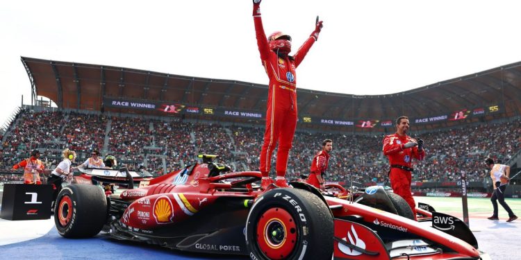 Piloto de Ferrari celebra de pie sobre su monoplaza tras ganar el Gran Premio de la Ciudad de México ante miles de aficionados.