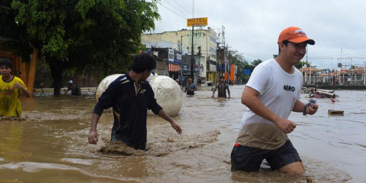 Personas caminan entre el agua tras las inundaciones en Poza Rica, Veracruz, luego del desbordamiento del río Cazones en octubre de 2025.