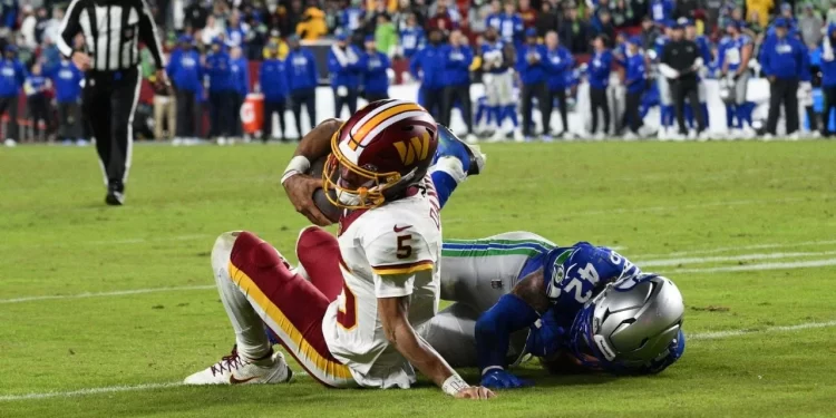 Jayden Daniels sale del campo tras sufrir una lesión en el hombro durante un partido de los Washington Commanders en la NFL 2025.