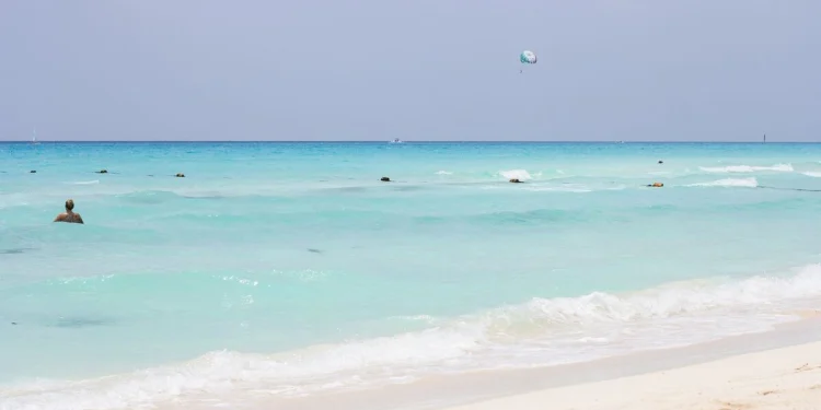 Bañistas en el mar turquesa de una playa pública en Playa del Carmen