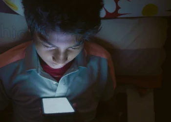 Adolescente usando su celular de noche