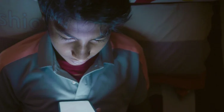 Adolescente usando su celular de noche
